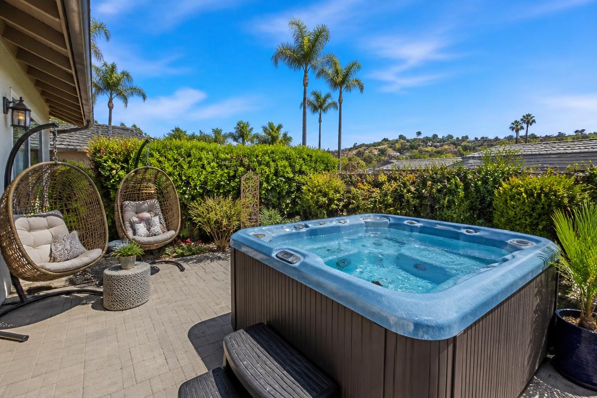 Light blue backyard hot tub on a paved patio with hanging chairs
